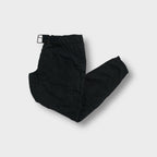Black Prada pants with quilted knee patches and an adjustable waist buckle.