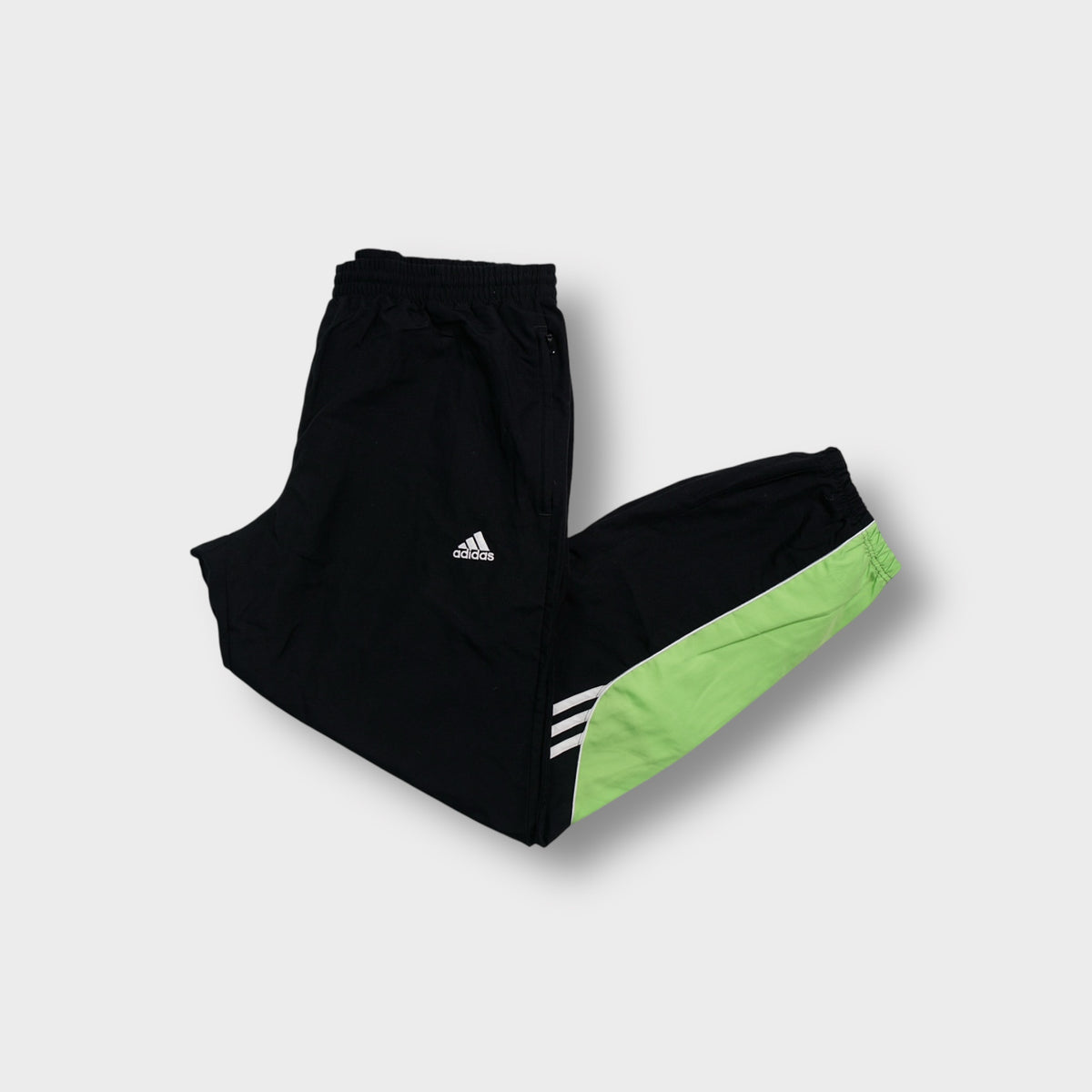 Adidas trackpants in black with green colour-block accent panel and white stripes.
