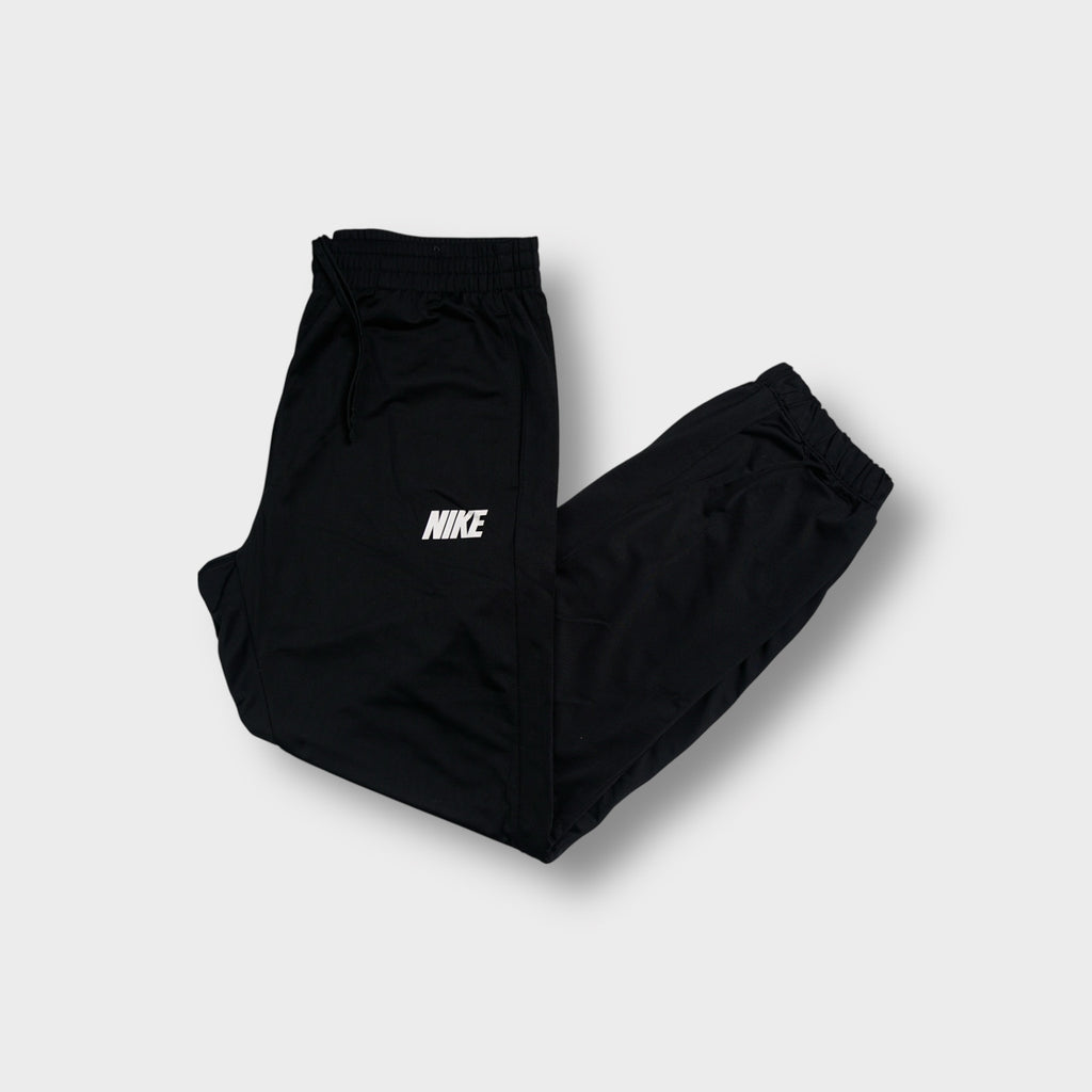 Nike trackpants in black featuring a white printed wordmark logo on the thigh
