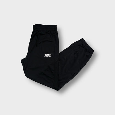 Nike trackpants in black featuring a white printed wordmark logo on the thigh