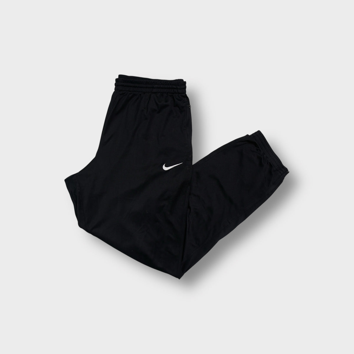 Nike trackpants in black with an embroidered white Swoosh logo on the upper thigh.