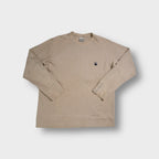 Beige Nike ribbed knit sweater featuring a small oval swoosh patch on the chest