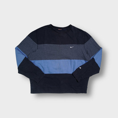 Blue Nike sweater featuring horizontal panels and a small white embroidered swoosh on the chest
