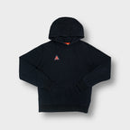 Nike ACG pullover hoodie in black with an embroidered orange and blue chest logo.