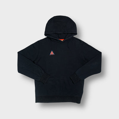 Nike ACG pullover hoodie in black with an embroidered orange and blue chest logo.