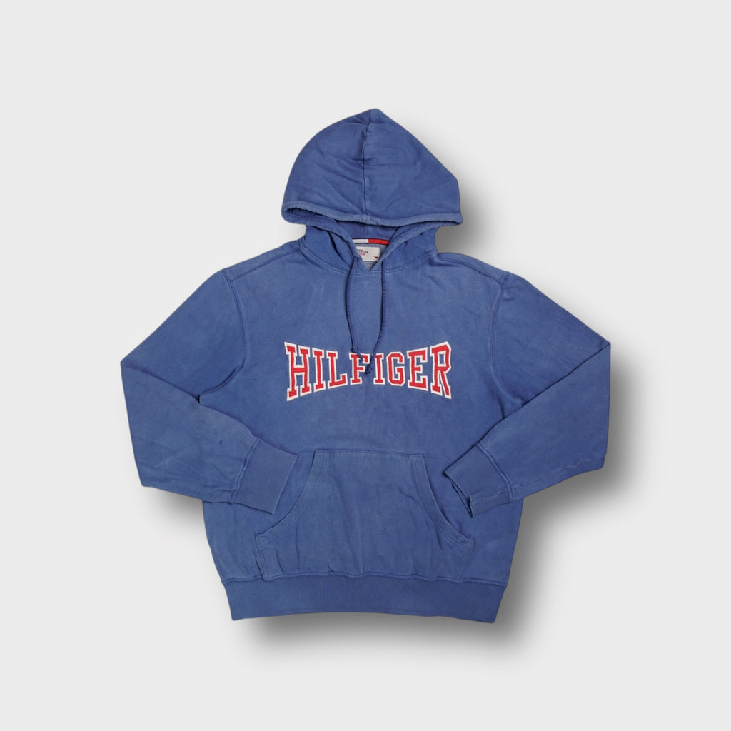 Blue Tommy Hilfiger pullover hoodie with red and white stitched Hilfiger chest appliqué.