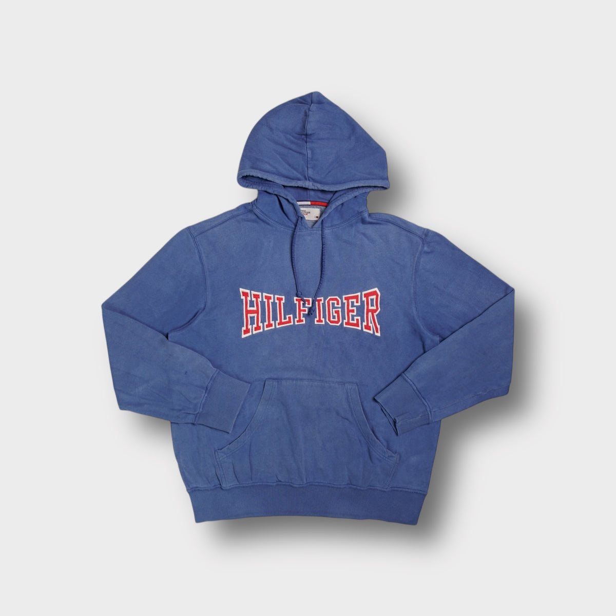Blue Tommy Hilfiger pullover hoodie with red and white stitched Hilfiger chest appliqué.