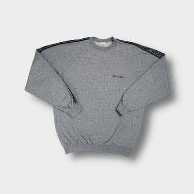 Champion grey crew-neck sweater featuring black logo tape trim along the sleeves.