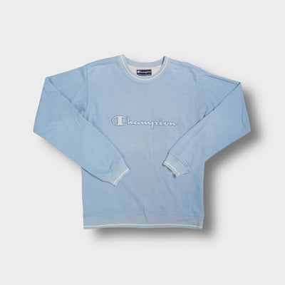 Light blue Champion crewneck sweater with white embroidered script logo across the chest