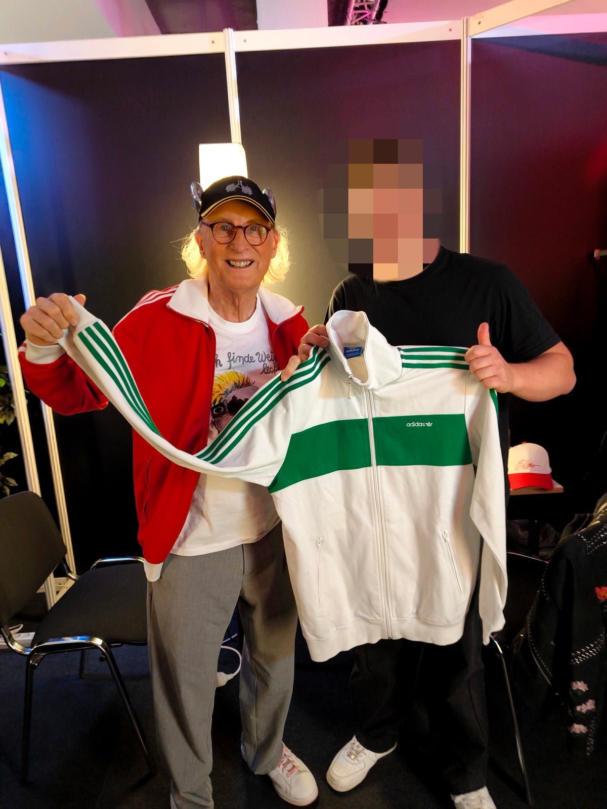 White and green Adidas track jacket from the ninetyvintage shop, held up at an event.
