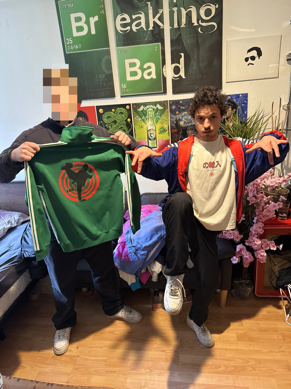 Green track jacket from the ninetyvintage shop, held up in a living room.