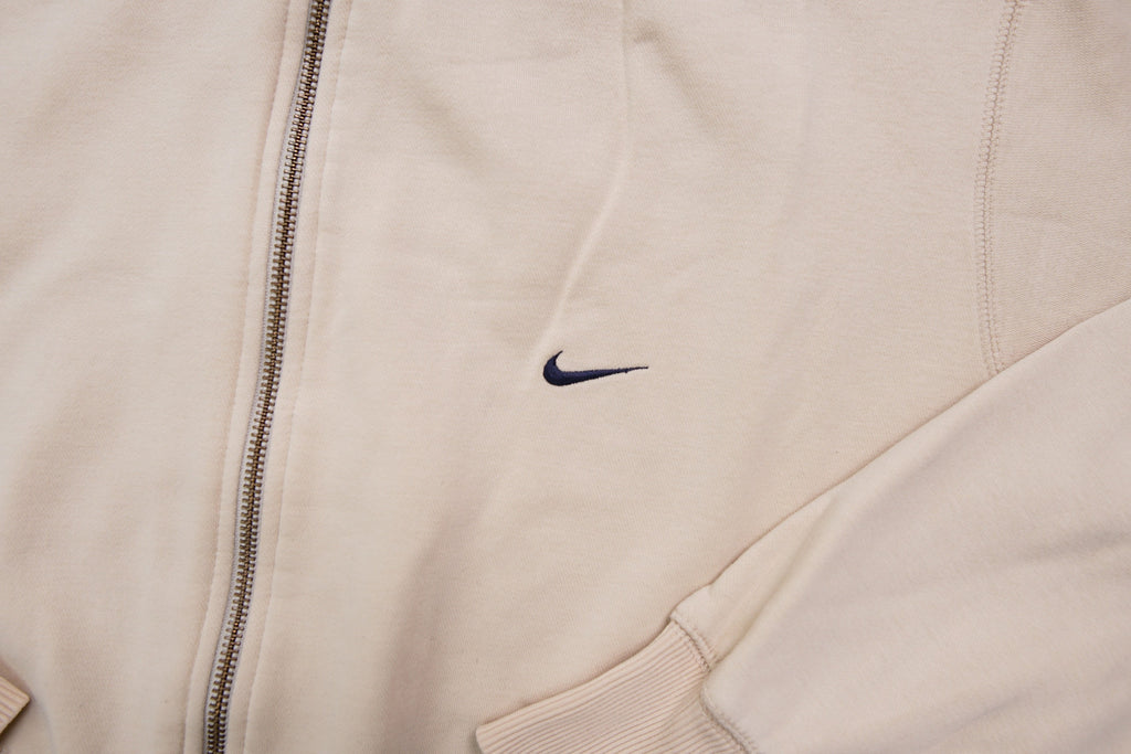Nike zip jacket in beige featuring a small navy embroidered swoosh on the chest, detail