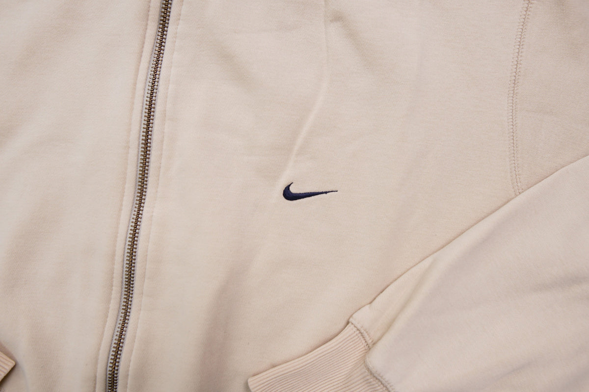Nike zip jacket in beige featuring a small navy embroidered swoosh on the chest, detail