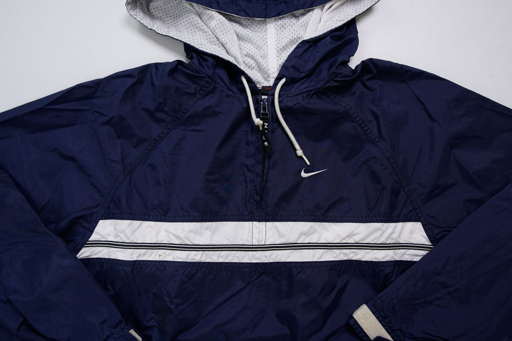 Nike navy jacket featuring a white chest stripe, hooded half-zip, and small embroidered swoosh, detail
