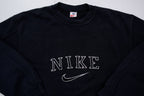 Black Nike sweater with embroidered white spellout logo and Swoosh on chest, detail