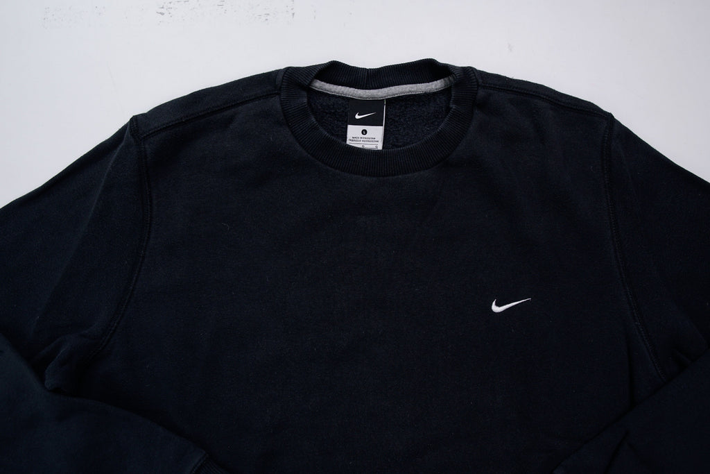 Nike sweater in black with small white embroidered swoosh on left chest, detail