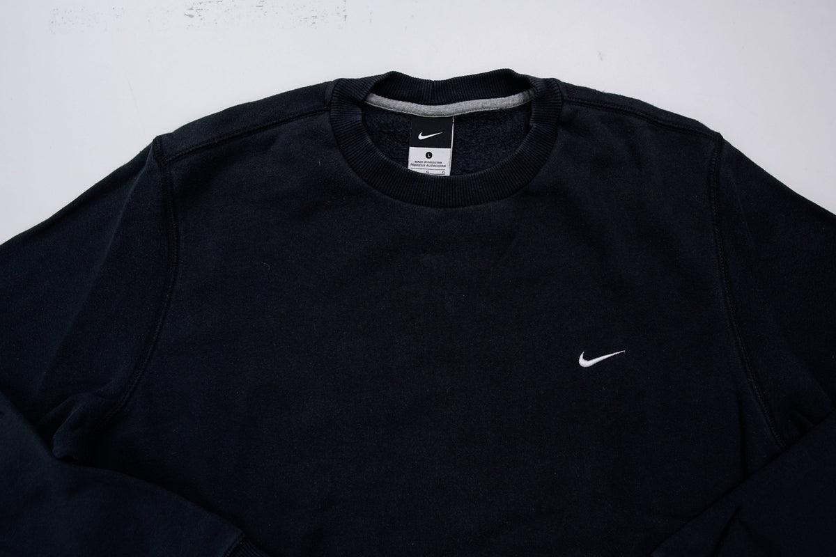 Nike sweater in black with small white embroidered swoosh on left chest, detail