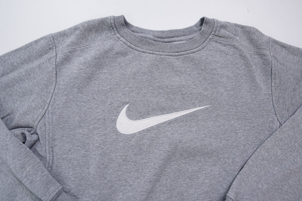 Nike crewneck sweater in grey with a large white embroidered swoosh applique on the chest, full view