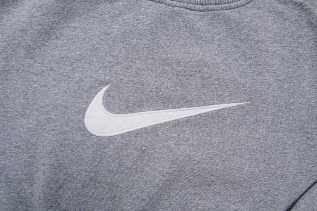 Nike crewneck sweater in grey with a large white embroidered swoosh applique on the chest, detail