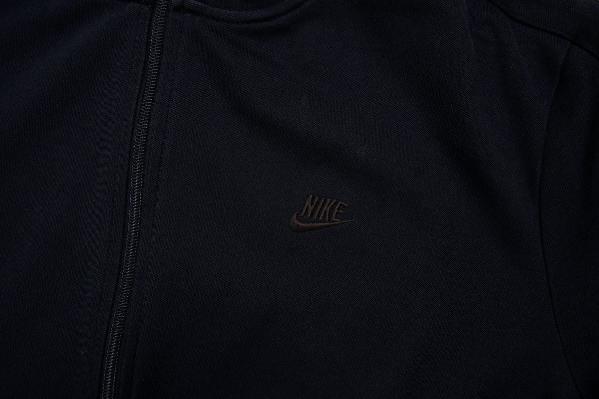 Nike track jacket in black featuring an embroidered swoosh logo on the chest, detail