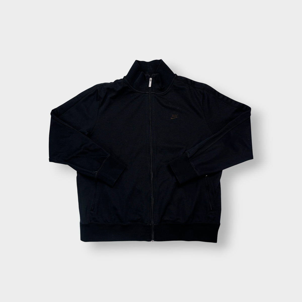 Nike track jacket in black featuring an embroidered swoosh logo on the chest