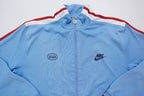 Light blue Nike jacket with red shoulder stripes and embroidered chest logo, detail