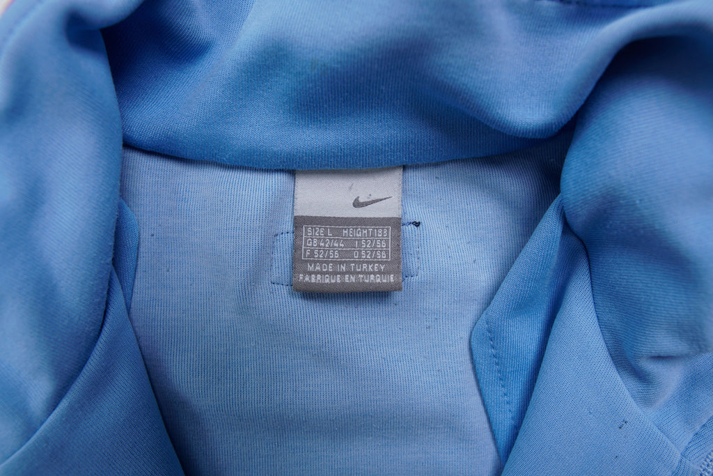 Light blue Nike jacket with red shoulder stripes and embroidered chest logo, size label