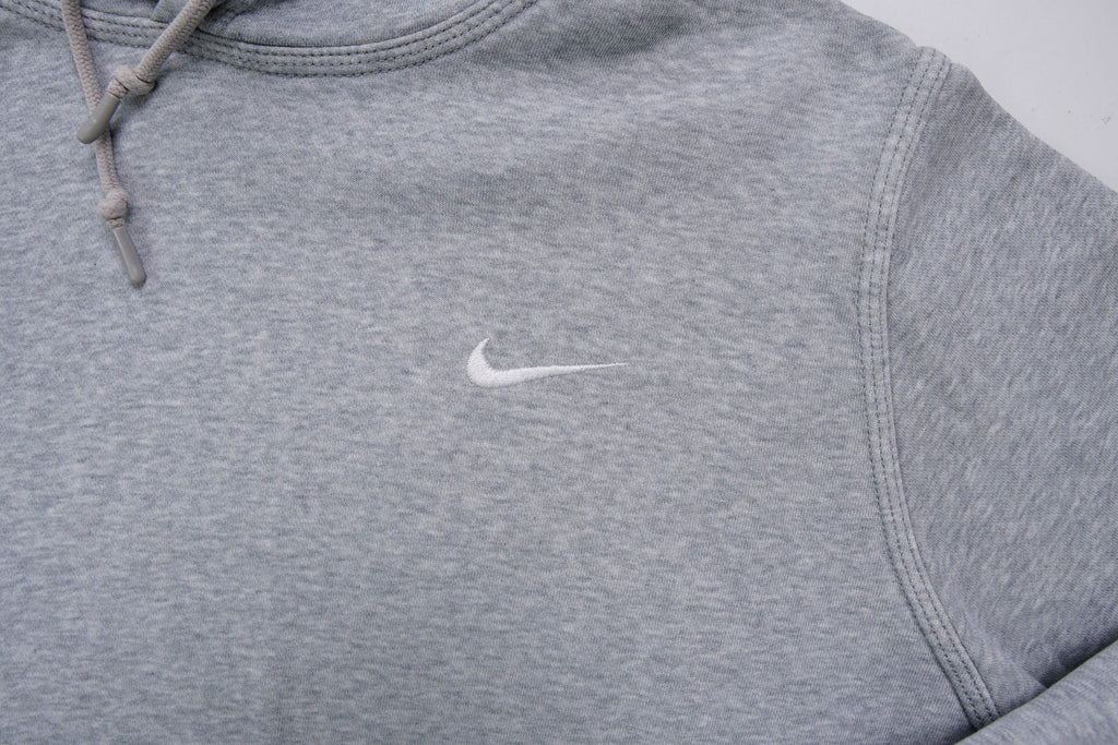 Nike grey hoodie sweater featuring a small white embroidered Swoosh logo on the chest, detail