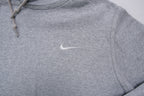 Nike grey hoodie sweater featuring a small white embroidered Swoosh logo on the chest, detail