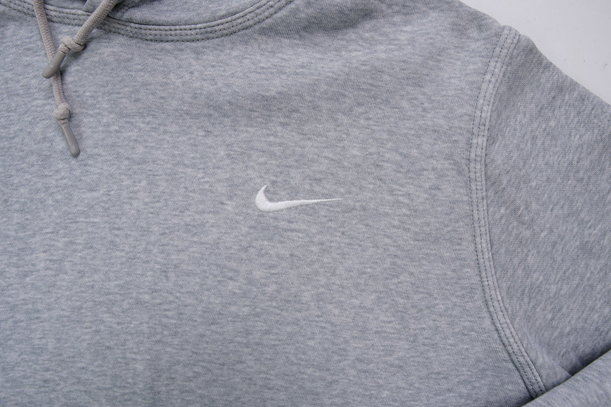 Nike grey hoodie sweater featuring a small white embroidered Swoosh logo on the chest, detail