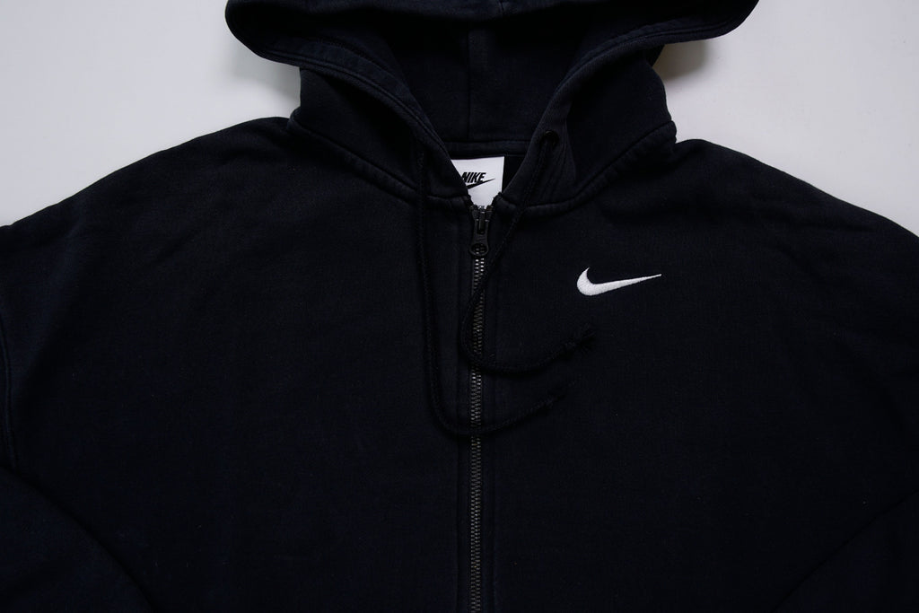 Black Nike zip jacket featuring a hood and embroidered white Swoosh on chest, detail