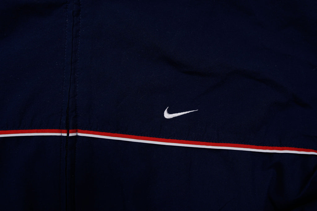 Navy Nike jacket featuring a white embroidered Swoosh logo and a red chest stripe, detail