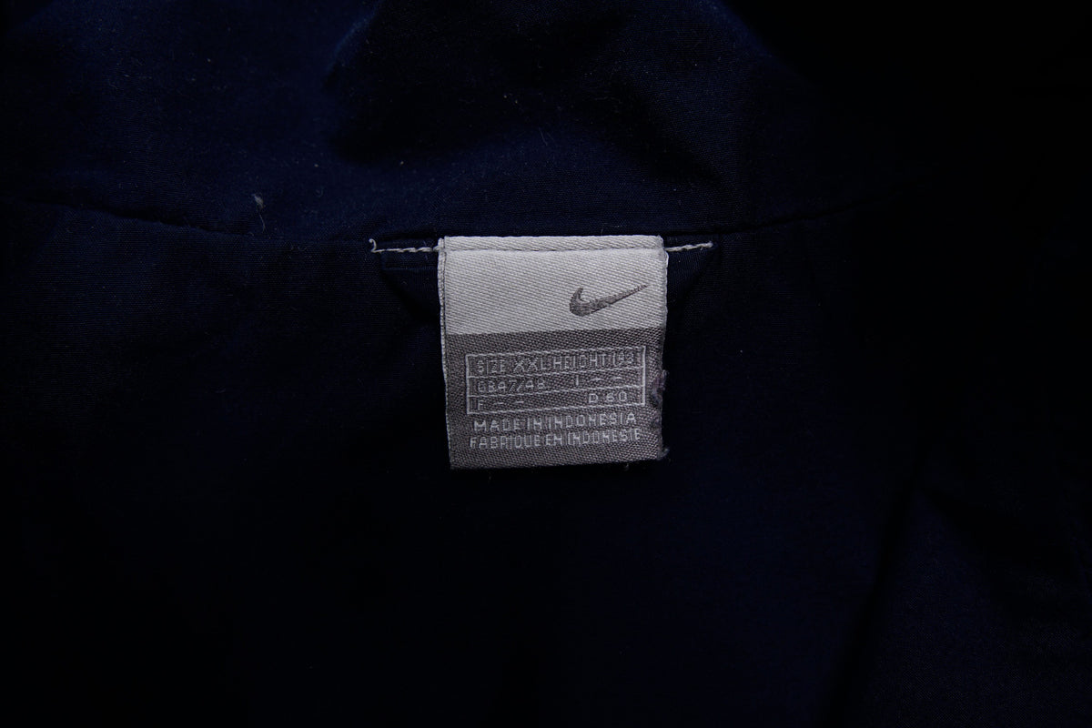 Navy Nike jacket featuring a white embroidered Swoosh logo and a red chest stripe, size label