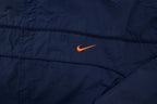 Nike jacket in navy featuring an embroidered orange Swoosh on the chest, detail