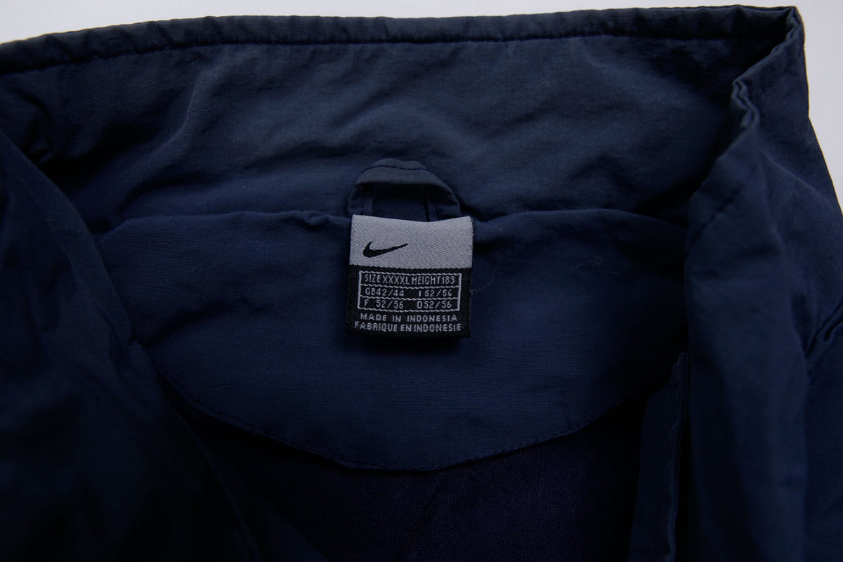 Nike jacket in navy featuring an embroidered orange Swoosh on the chest, size label