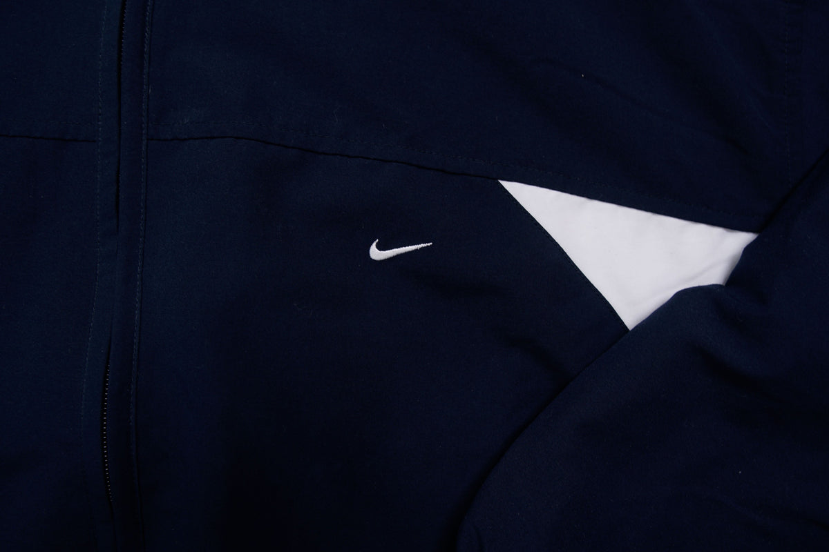 Nike zip-up track jacket in navy with red side panels and a small white swoosh logo, detail