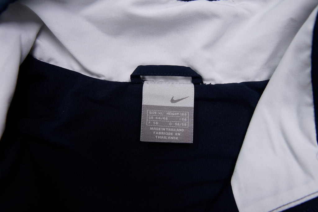 Nike zip-up track jacket in navy with red side panels and a small white swoosh logo, size label