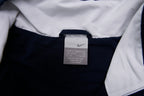 Nike zip-up track jacket in navy with red side panels and a small white swoosh logo, size label