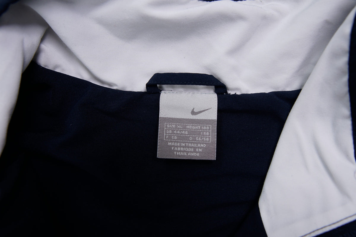 Nike zip-up track jacket in navy with red side panels and a small white swoosh logo, size label
