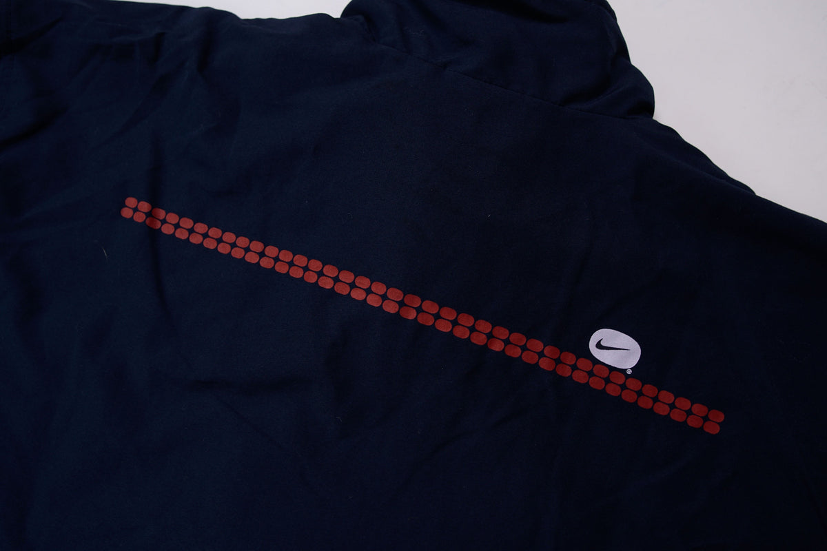 Nike zip-up track jacket in navy with red side panels and a small white swoosh logo, back view